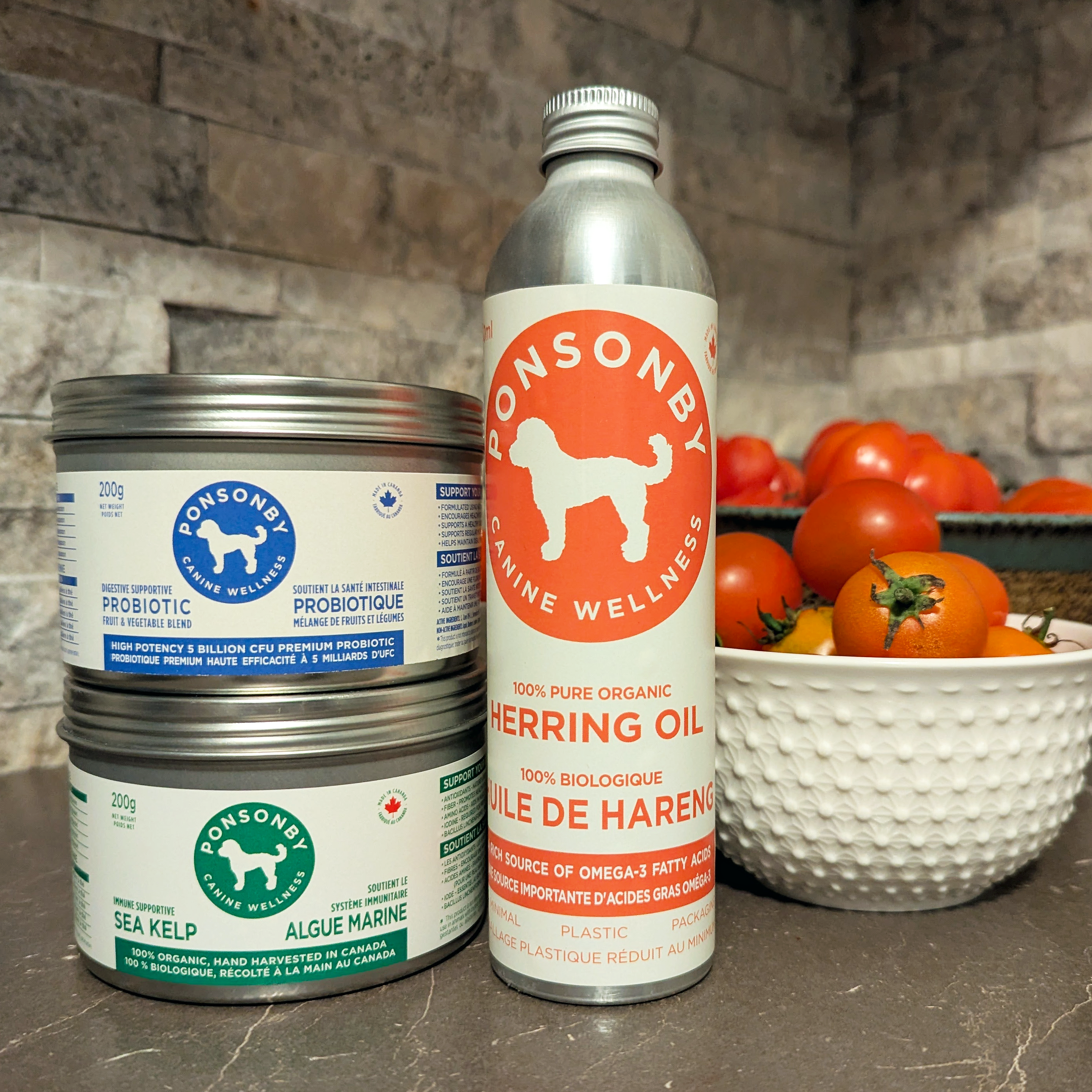Three Ponsonby pet product containers on a stone surface with tomatoes in the background.